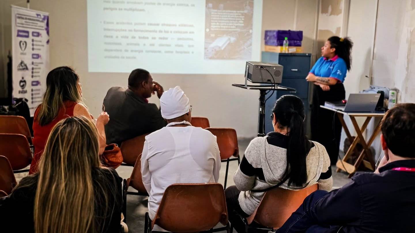 Turma acompanha uma aula de capacitação com projetor no salão do Instituto AMEAS.