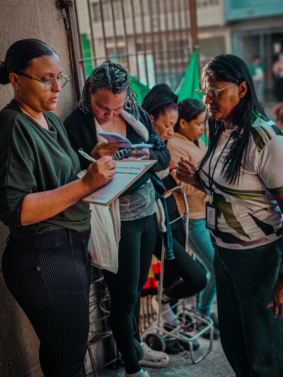 Voluntária do Instituto AMEAS acompanha moradoras no preenchimento de fichas durante um atendimento.