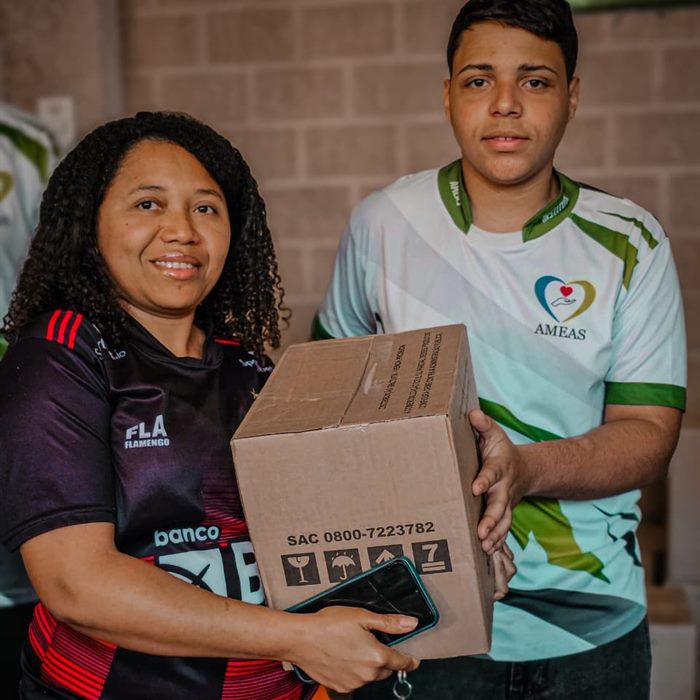 Moradora recebe uma caixa de donativos das mãos de um voluntário do Instituto.