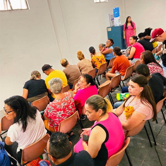 Moradores reunidos em cadeiras durante um encontro comunitário no salão do Instituto.